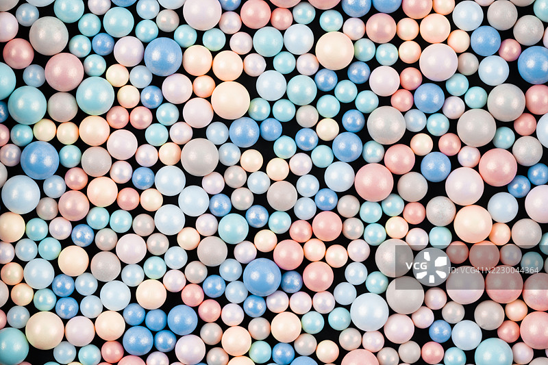 多彩的粉彩珠子背景。不同颜色的闪亮塑料珠子混合，俯视图。图片素材