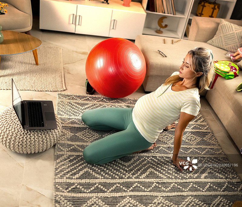 孕妇在家进行在线普拉提锻炼图片素材