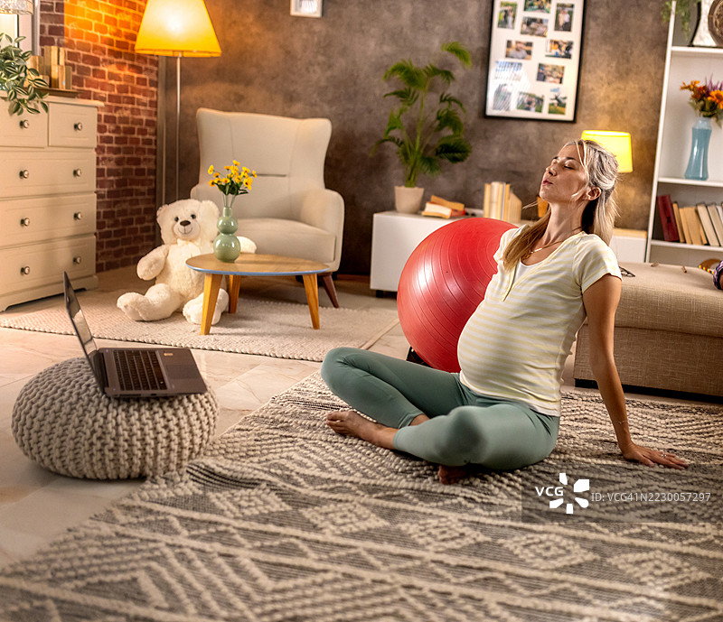 孕妇在家进行在线普拉提锻炼图片素材