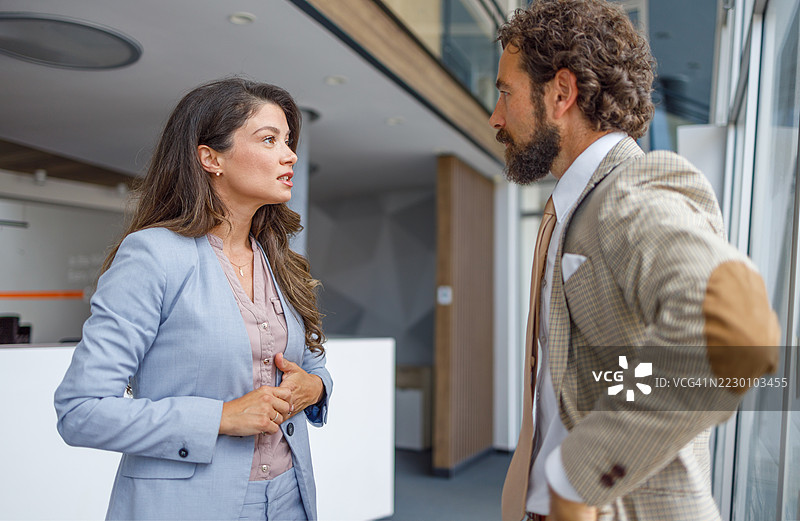 女商人在办公室走廊与男商人交谈图片素材