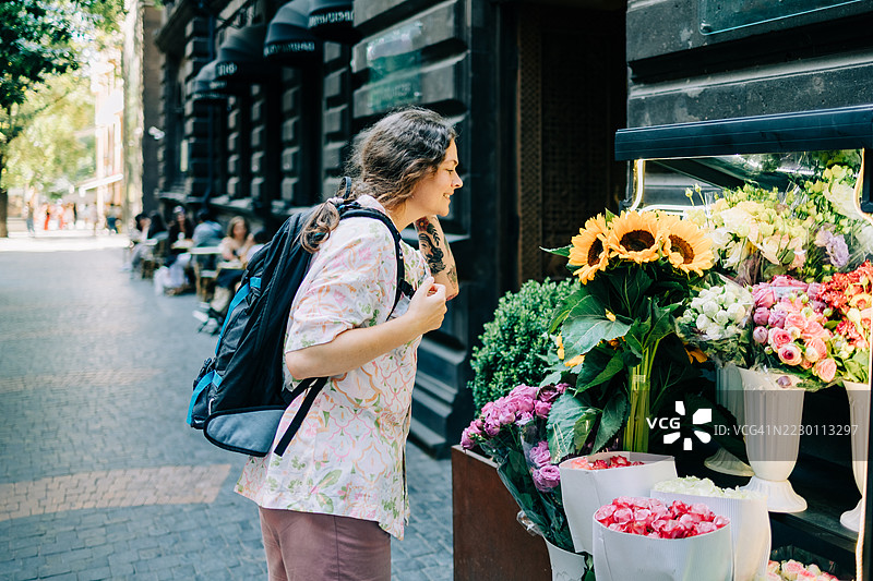 游客在城市的花店里闻五彩缤纷的花朵图片素材