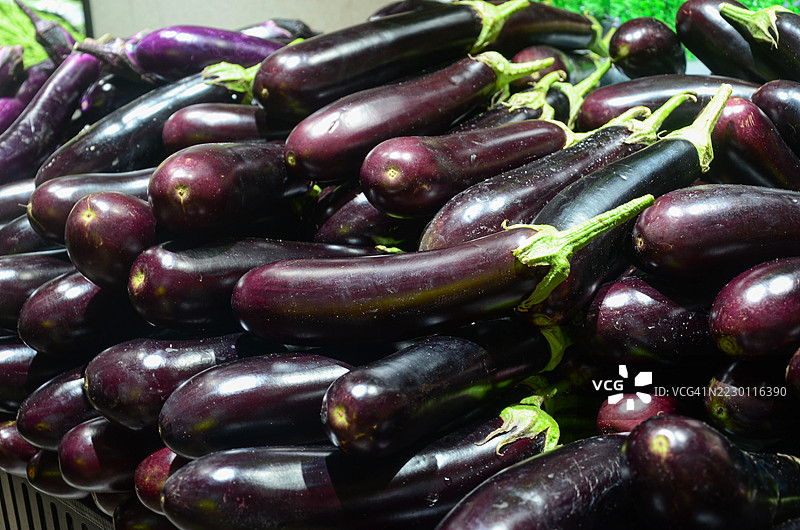 超市货架上的新鲜紫色茄子待售。现代超市生鲜区展示着鲜艳的紫色茄子。图片素材