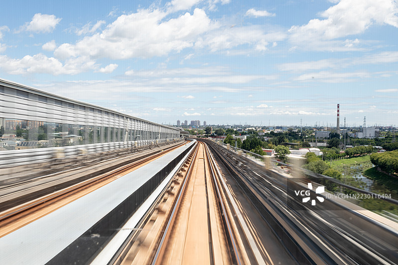 地铁列车在中国北京的城市高架道路旁行驶图片素材