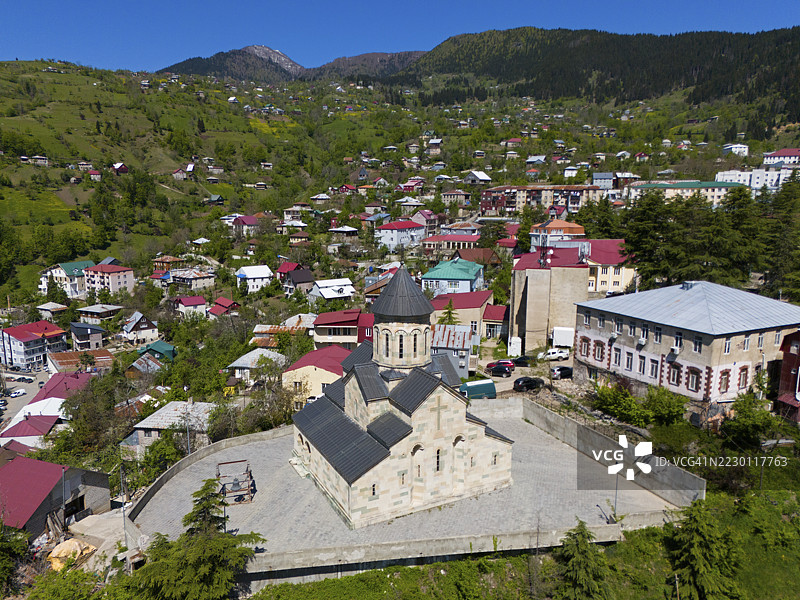 亚美尼亚安德鲁·阿波斯托尔教堂,库洛,库洛,阿扎拉自治共和国,阿扎拉,小高加索,格鲁吉亚,俯瞰被绿色山丘和许多彩色房屋环绕的山村教堂,天空湛蓝图片素材