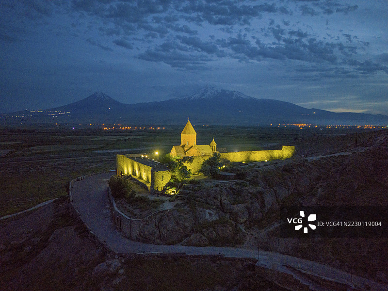 夜幕下的修道院在黄昏时分的宁静山景中被照亮，俯瞰视角，乔尔维拉普修道院，深邃的地牢，阿拉拉特山和小阿拉拉特山在背景中，位于土耳其，阿拉拉特省，亚美尼亚图片素材