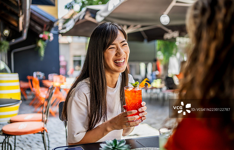 年轻女性在户外咖啡馆享用清爽的鸡尾酒图片素材