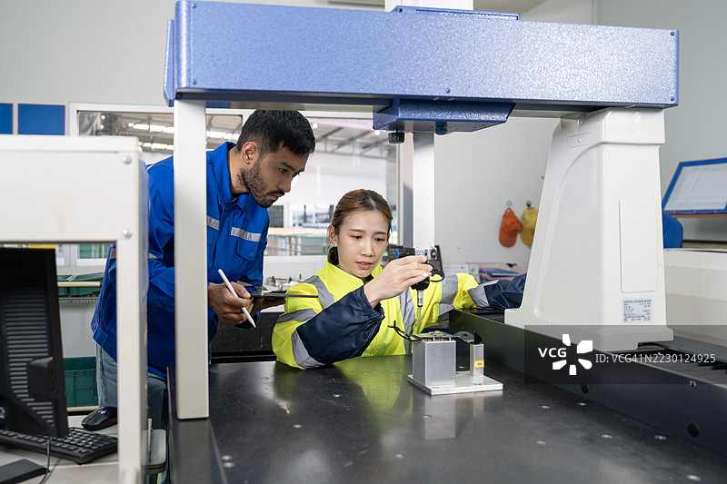 两名检查员使用坐标测量机（CMM）。图片素材