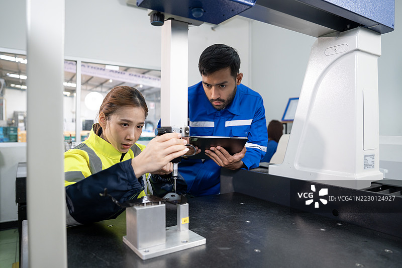 两名检查员使用坐标测量机（CMM）。图片素材