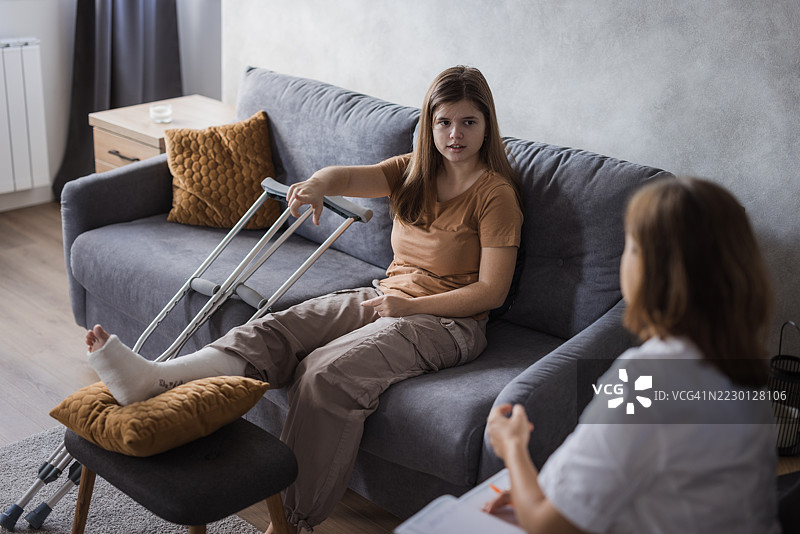 年轻女性因腿部骨折正在接受医生的上门拜访图片素材