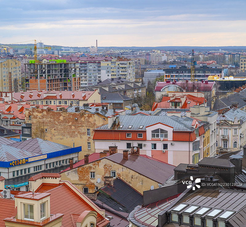 鸟瞰视角展现伊万诺-弗兰科夫斯克市景，融合了多种建筑风格，五彩斑斓的屋顶，建筑起重机在阴云密布的天空中耸立。图片素材