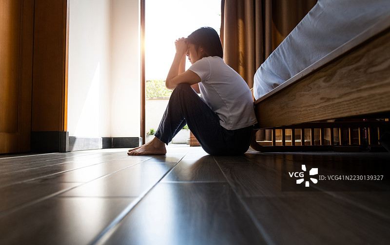 抑郁的女人独自坐在卧室的地板上图片素材