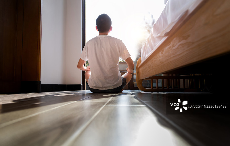 男子坐在地板上以莲花坐姿放松的背影图片素材