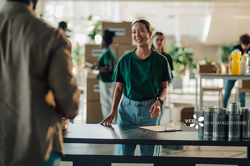 年轻的亚洲女性志愿者在食品银行工作，接受捐赠图片素材