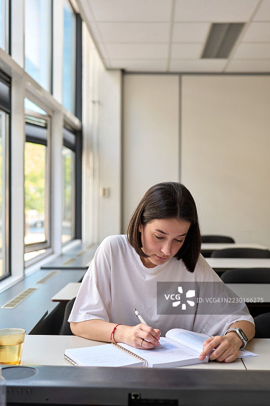 年轻学生在大学教室里做笔记图片素材