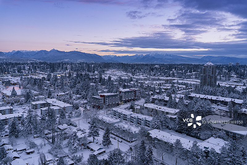 黄昏时分的冬季小镇景观，雪覆盖的建筑和山脉，温哥华，加拿大图片素材
