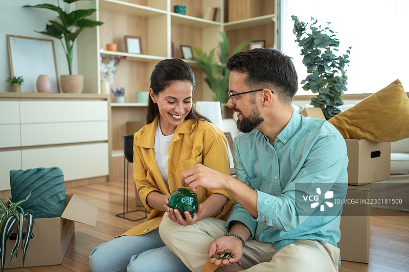 年轻情侣在储蓄罐里存钱，为新家做准备图片素材