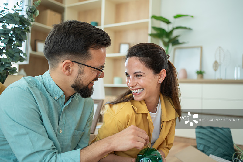 快乐的情侣在新家一起存钱图片素材