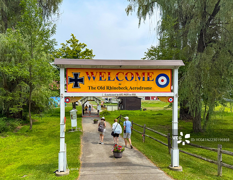 人们在红钩的老莱茵贝克航空博物馆欢迎标志下走过图片素材