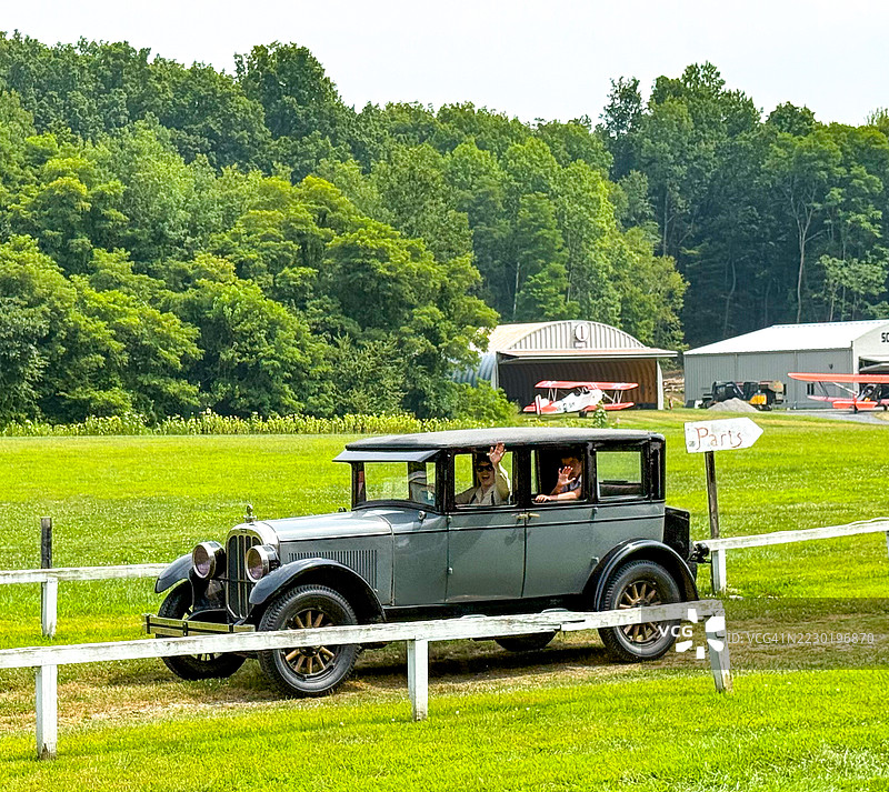 人们在红钩的老莱茵贝克航空博物馆的古董车上挥手。图片素材