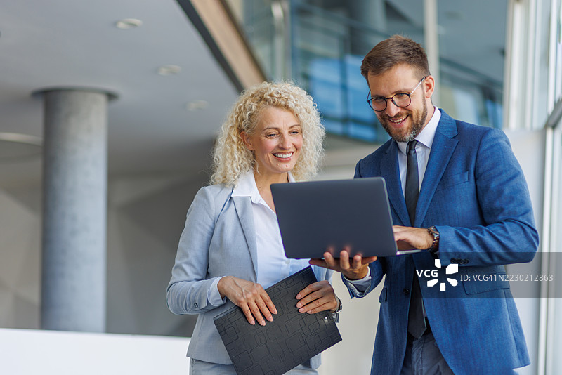 商务人士在办公大楼内共同使用笔记本电脑工作图片素材