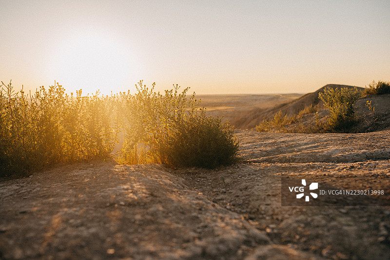 阳光洒在风景上，为崎岖的地形和稀疏的植被投下温暖的光辉。图片素材