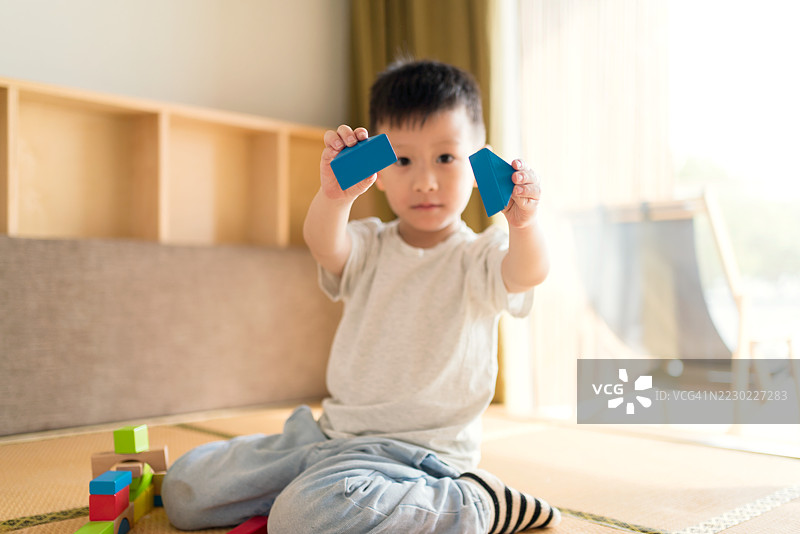 亚洲小孩在家里独自玩积木。图片素材