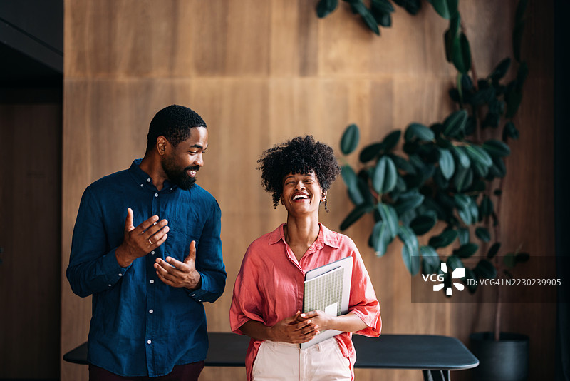 同事们在现代办公室环境中分享欢笑图片素材