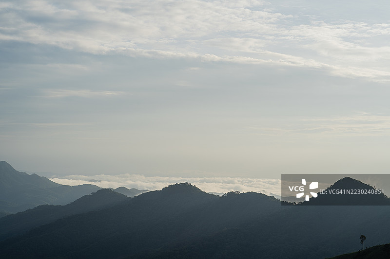 宁静的山景，柔和的晨光，地平线上云层，轮廓分明的山脊渐渐消失在远方。图片素材