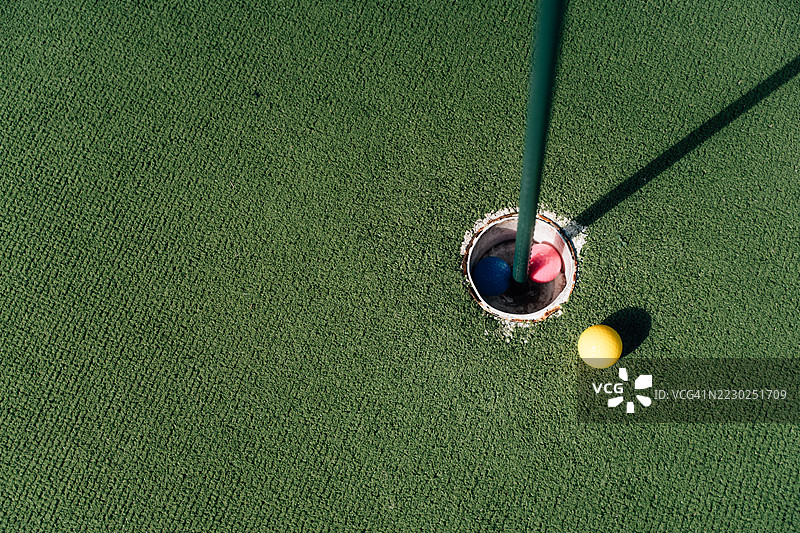 迷你高尔夫球场的俯视图，包含发球台和洞中的球图片素材