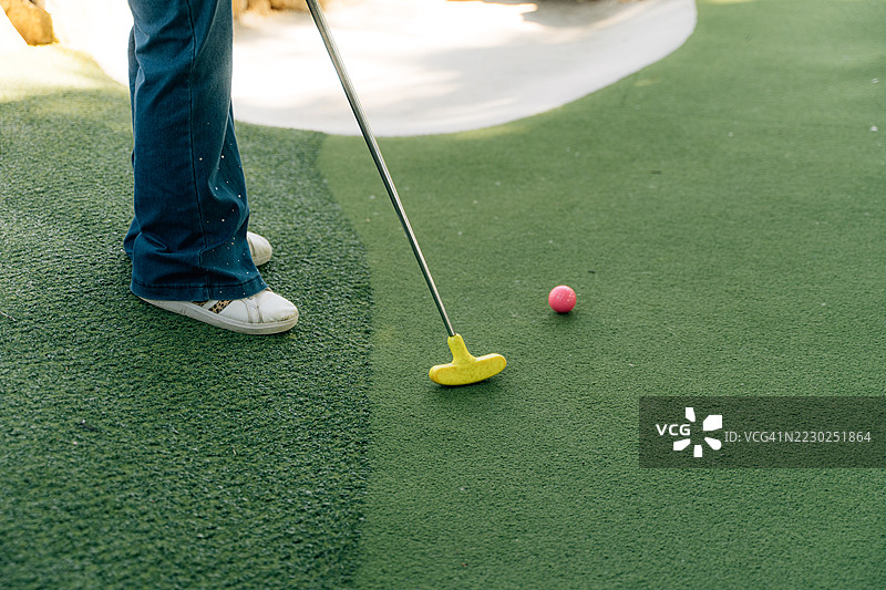 迷你高尔夫球场，带有发球台和粉色球，孩子在玩耍图片素材