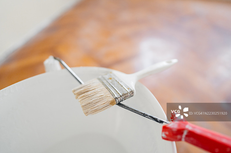 一个空置的正在装修的公寓里，油漆桶上的油漆刷图片素材