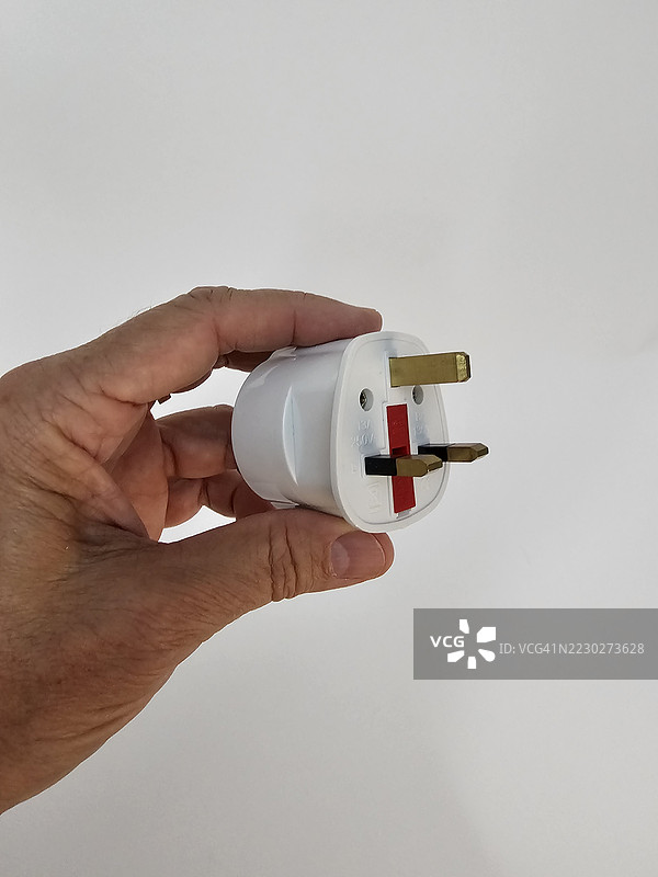人手中握着的英国插头适配器正面视图图片素材