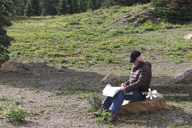 坐在岩石上的男人在画画图片素材