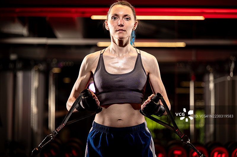 强壮的年轻女性在健身房使用拉索训练机锻炼图片素材