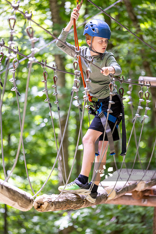 年轻男孩在夏季的绳索公园中玩得很开心图片素材