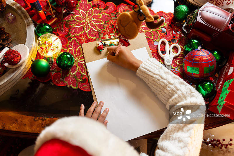 女孩从上方视角写信给圣诞老人。图片素材
