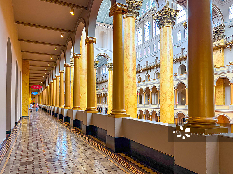 人们在华盛顿特区国家建筑博物馆的大礼堂走廊中走动，周围有柱子。图片素材