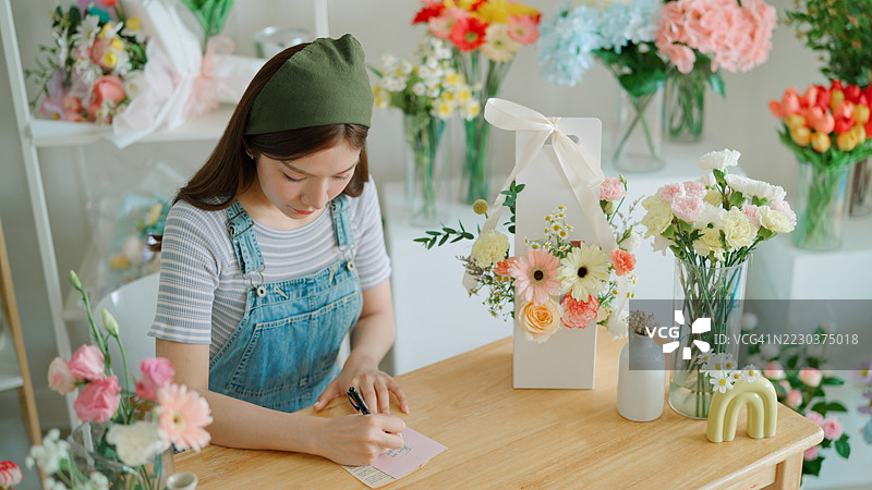 花店老板在贺卡上写祝福语，为花束增添情感图片素材