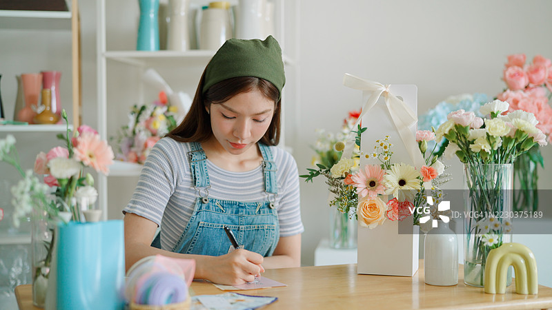 花店老板在贺卡上写祝福语，为花束添彩图片素材