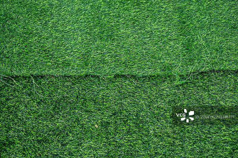 一块未完成的绿色人造草坪，表面有皱褶。人造草坪用于覆盖运动场或花园。图片素材