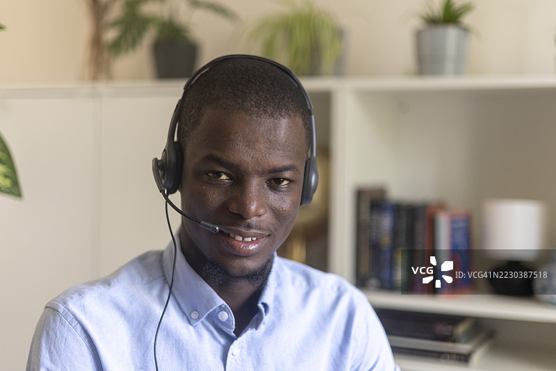 戴着耳机的黑人专业人士，微笑着远程工作图片素材