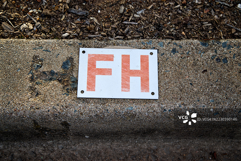 混凝土路边沟上的“FH”标志，指示消防栓的位置图片素材