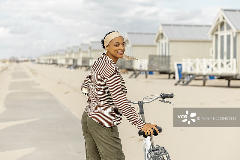 多元化的成年女性在海滩上骑自行车享受一天的时光图片素材