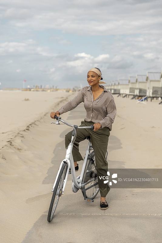 多元化的成年女性在海滩上骑自行车享受一天的时光图片素材