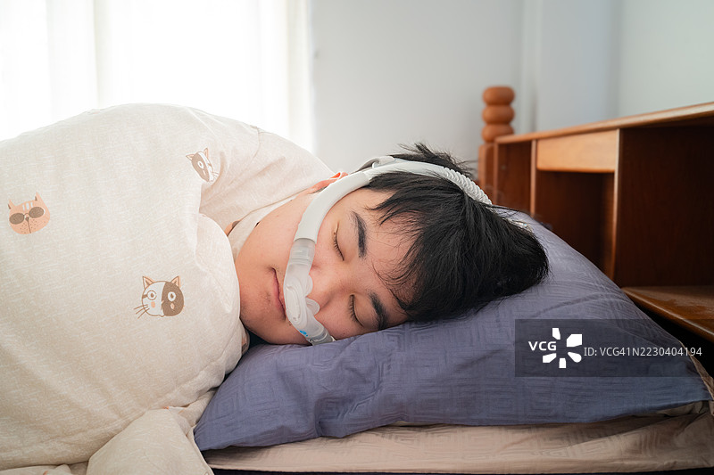 使用CPAP机进行睡眠呼吸暂停治疗的男子正在睡觉图片素材