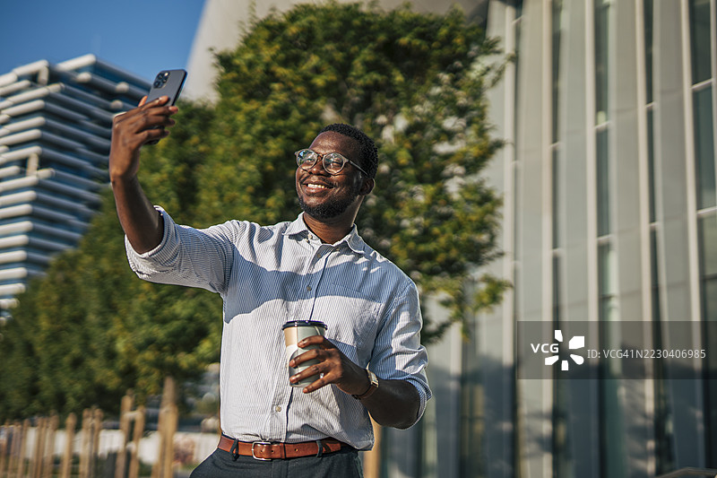 微笑的商人在办公室外喝咖啡时自拍图片素材
