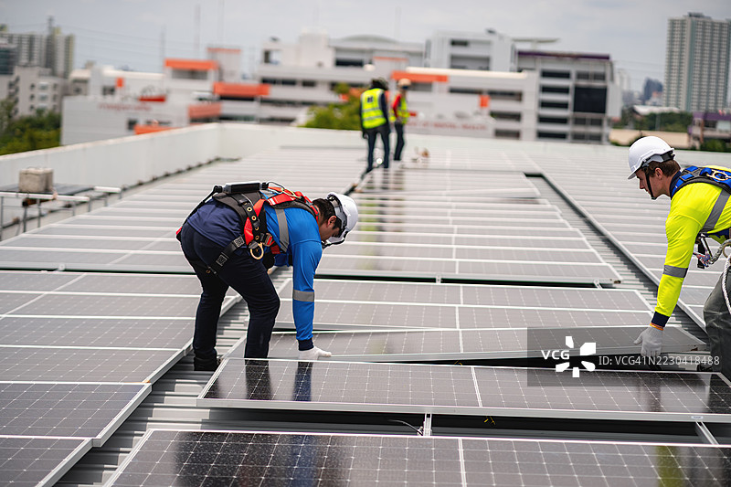 工程师和技术人员正在为建筑物的屋顶安装太阳能电池板，清洁能源技术概念，可再生能源。图片素材