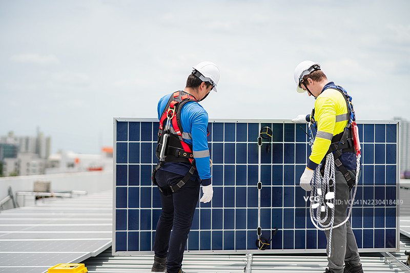 工程师和技术人员正在为建筑物的屋顶安装太阳能电池板，清洁能源技术概念，可再生能源。图片素材