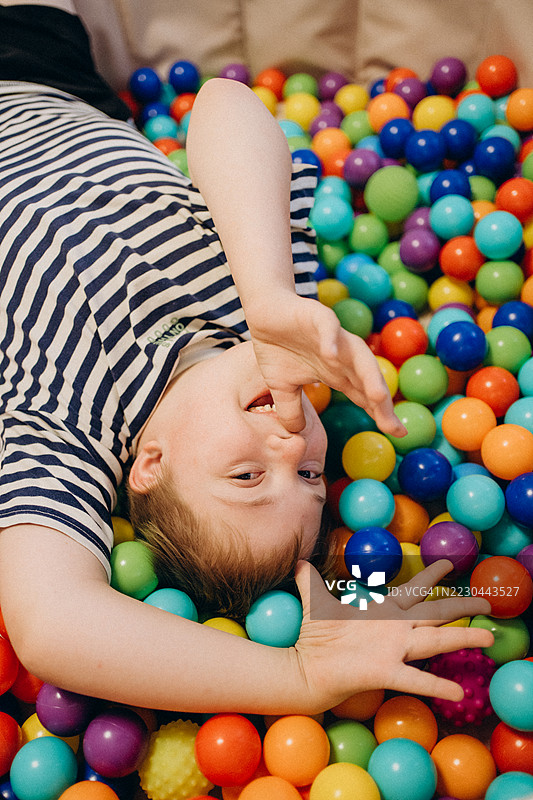 快乐的孩子躺在五彩斑斓的球池中玩耍图片素材