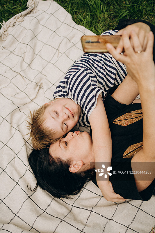 母亲和患有唐氏综合症的儿子躺在毯子上自拍图片素材